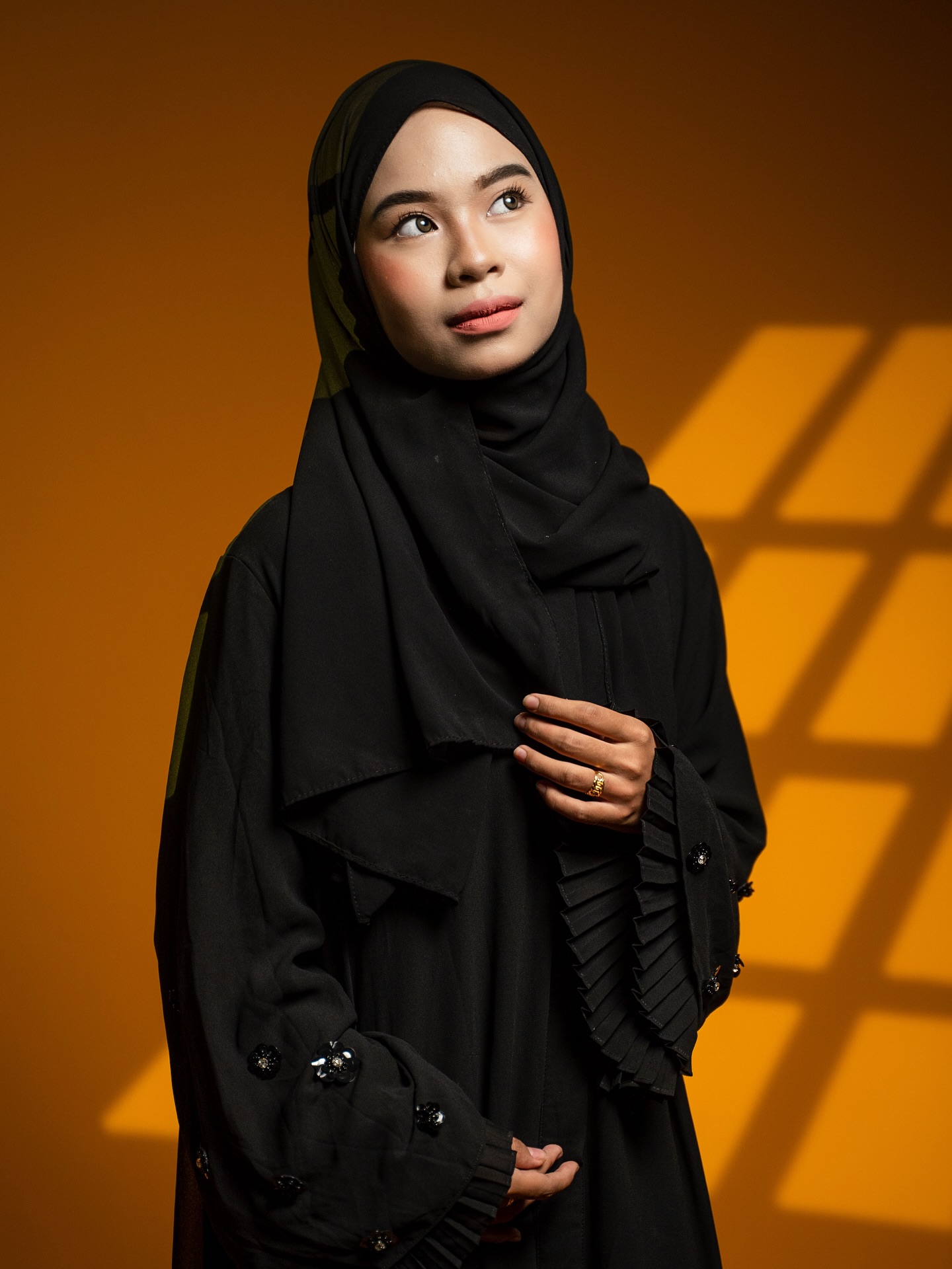 Studio portrait in black against a warm orange background
